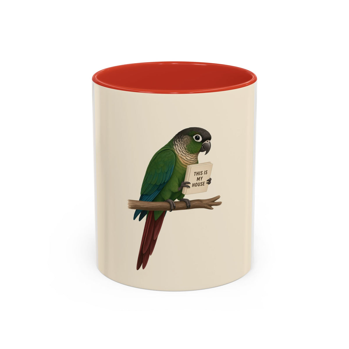 A ceramic mug with a white and cream-colored exterior and a red interior, featuring a printed illustration of a green parrot perched on a branch holding a sign that reads 'THIS IS MY HOUSE'.